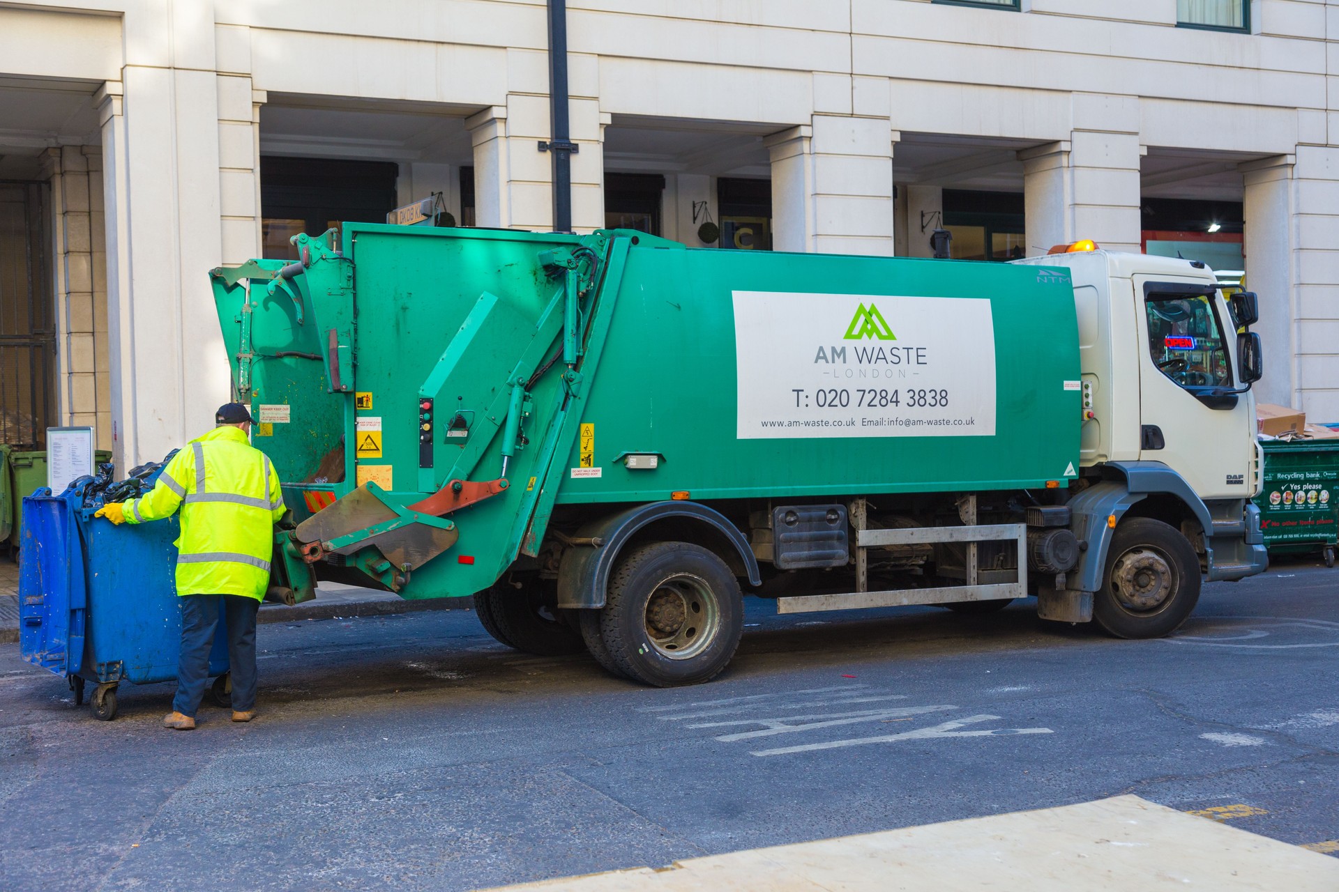 London, England - 10 April 2017 - Garbage collector operates his lift to load the trash from is container into his truck in London, England on April 10, 2017